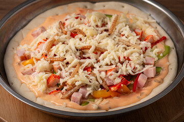 Insect Pizza tray prepared to bring into the oven consisting of various ingredients toppings such as shredded cheese, ham, sausage, sausage, bamboo worm, pupa, and silkworm edible. Close-up