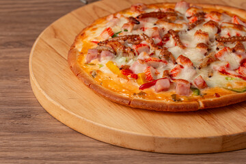 Delicious-looking insect pizza on a wooden serving board. The melted cheese covered with the vibrant colors of the toppings, such as ham, sausage, bamboo worm, pupa, silkworm edible. Close-up