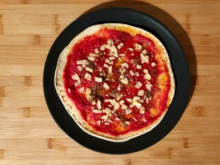 Piada Pizza: Fusion of Italian Flatbread with Tomato Sauce and Cheese on Black Plate