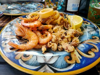 Delicious Fried Seafood Plate with Crispy Shrimp and Calamari on Decorative Italian Ceramic