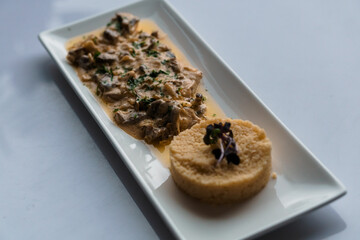 Couscous porridge with meat and mushroom sauce on a white plate