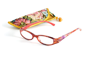Reading glasses with floral patterned eyeglass cases isolated on a white background. The glasses...