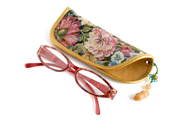 Reading glasses with floral patterned eyeglass cases isolated on a white background. The glasses have a bold red frame, a blend of functionality and style, with practical eyeglasses.