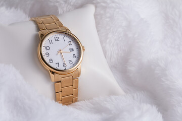 Gold luxury wristwatch, Made of a gold-toned metal on a white background with depth of field. Close-up
