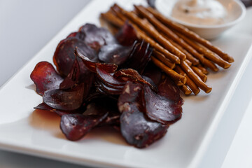 Sliced meat with sauce and breadsticks