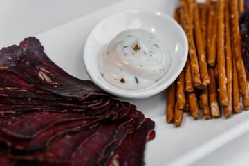 Sliced meat with sauce and breadsticks