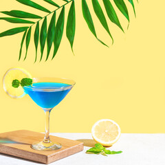 Blue cocktail with lemon and palm leaf