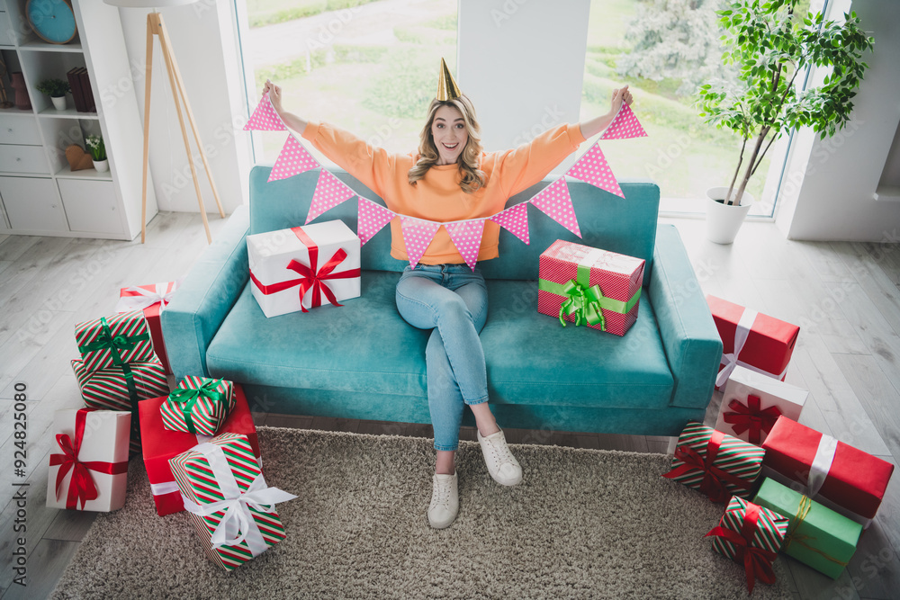 Sticker Full body photo of nice young girl sit sofa excited celebrate birthday hold flags wear orange clothes modern interior flat indoors