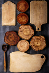 Old wooden cutting boards and tree trunk slices on black chalkboard background. Flat lay. Top view. Food concept.