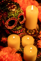 Top view of a decorated skull with metal flowers, surrounded by vibrant orange marigolds and candles