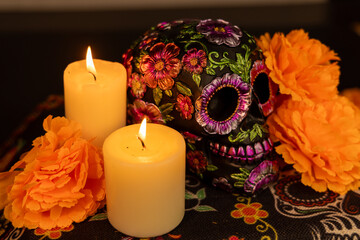 A skull intricately decorated with metal flowers and surrounded by bright orange marigolds. The...