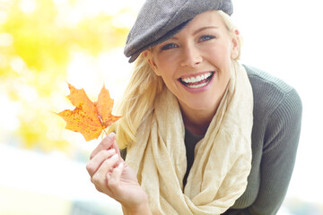 Autumn, travel and woman with leaf in portrait for outdoor vacation, environment and season change. Female person, happy and adventure with foliage in park for nature, peace and holiday in Canada