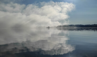 Fototapeta premium The sky is reflected in the water, the lake, the clouds are reflected in the water, morning on the lake, fog on the lake, morning fog