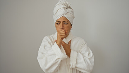 Woman coughing in a white bathrobe with a towel on her head against an isolated white background