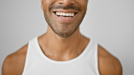 Close-up of a cheerful young hispanic man with a beard, wearing a white tank top, isolated on a white background.