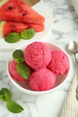 Scoops of tasty watermelon sorbet with mint in bowl on white marble table