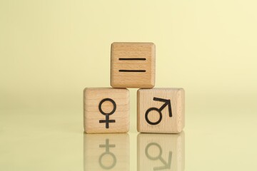 Gender equality concept. Wooden cubes with male and female symbols on light yellow background