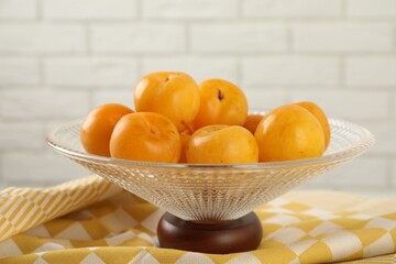 Glass vase with fresh plums on table, closeup