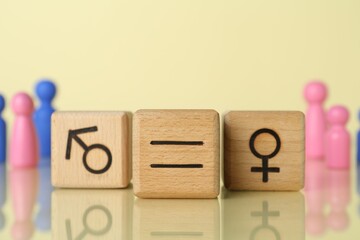 Gender equality concept. Wooden cubes with male and female symbols on light yellow background