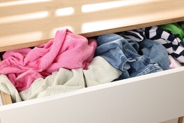 Cluttered chest of drawers indoors, closeup. Clothes in mess