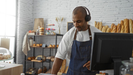 Handsome young man working in a bakery shop with shelves of fresh bread in the background