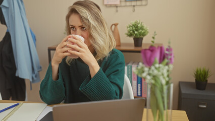 A contemplative young woman sipping coffee in a cozy home office environment, showcasing a modern, casual lifestyle.