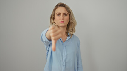 Obraz premium A young woman with blonde hair giving a thumbs down gesture isolated against a white background