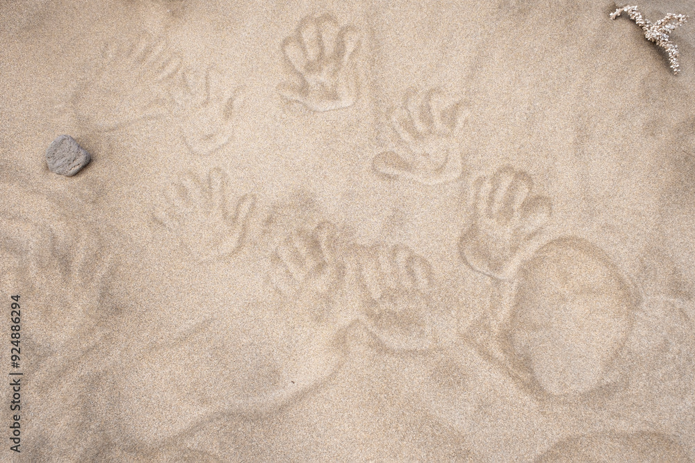 Wall mural top view of human handprints on the beach sand, beach sand texture with traces of human hands