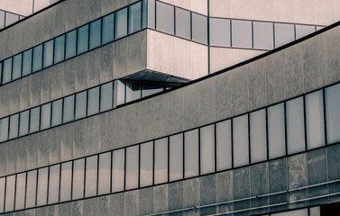 gray high concrete building with reflection of the sky and clouds in the windows
