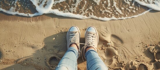 Young woman s feet in sporty shoes and jeans resting on a sandy beach perfect for motivational quotes blogs or your text with a vast panoramic view for a backdrop image. Creative banner