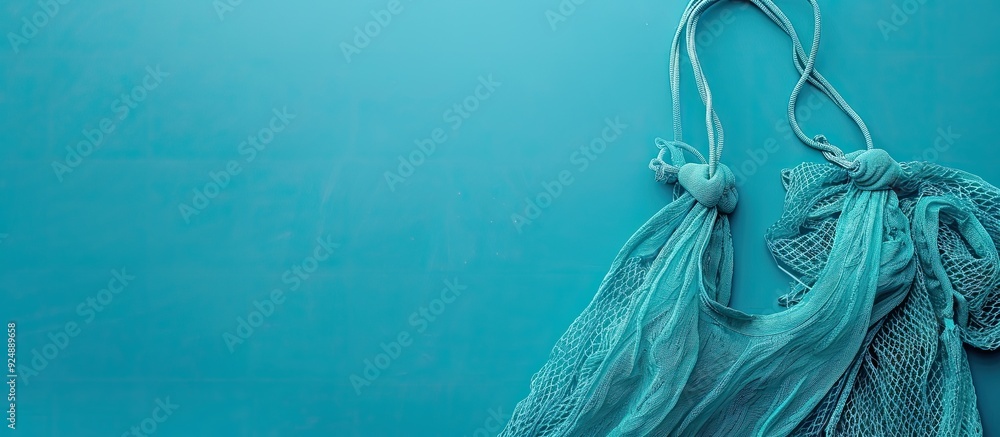 Poster Zero waste or plastic free concept illustrated with a mesh bag against a blue backdrop The view is horizontal from the top allowing for copy space image
