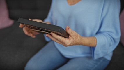 Senior woman holding a photo frame indoors, reflecting on memories.