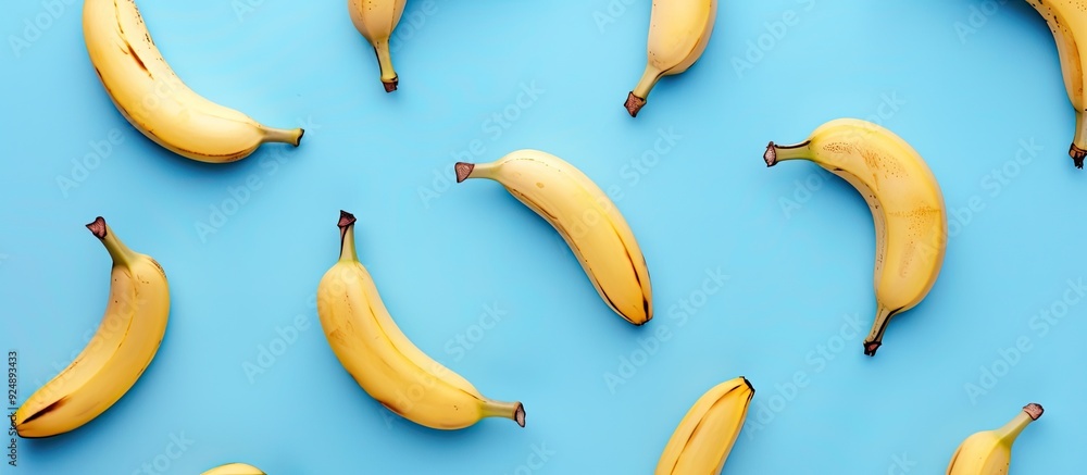 Poster Top view of a healthy and simple raw food concept with a banana pattern on a blue background in a flat lay style shot with copy space image