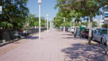 Blurred outdoor sidewalk scene featuring trees, cars, and streetlights on a sunny day, creating a defocused summer atmosphere in a bustling urban area