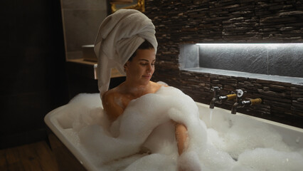A serene woman enjoys a bubble bath in a stylish bathroom, emulating relaxation and luxury.