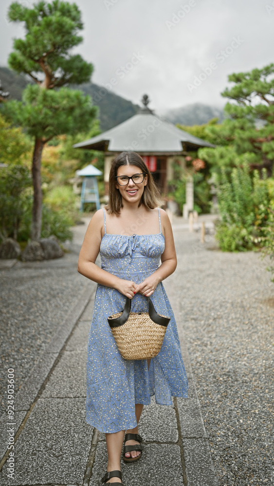 Wall mural Cheerful, beautiful, hispanic woman with glasses walks confidently towards the camera, her glowing smile lighting up the historic kyoto temple in the background. joyful travel in japan!