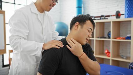 A male physiotherapist treats a male patient's neck pain in a clinic's therapy room