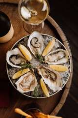 Fresh oysters on ice with lemon wedges and white wine, ideal for gourmet dining and celebrations