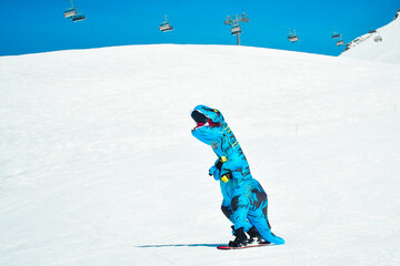 Gudauri, Georgia - 15th february, 2024: front view skier wear blue dinosaur costume snowboard...