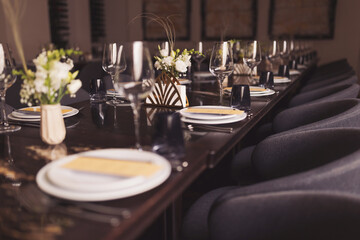 luxury tableware beautiful table setting in restaurant. banquette luxury arrangement plates and glasses. Glasses, forks, knives, napkins and decorative flower on a dark old brown wooden table.