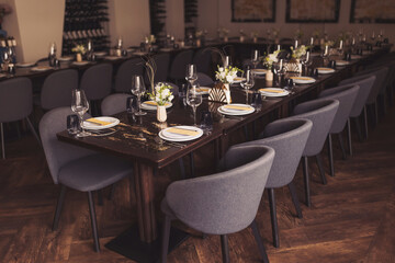 luxury tableware beautiful table setting in restaurant. banquette luxury arrangement plates and glasses. Glasses, forks, knives, napkins and decorative flower on a dark old brown wooden table.