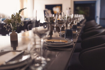 luxury tableware beautiful table setting in restaurant. banquette luxury arrangement plates and glasses. Glasses, forks, knives, napkins and decorative flower on a dark old brown wooden table.
