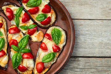 Italian mini pizza . Aubergine (eggplant ) with mozzarella cheese and basil . On rustic background