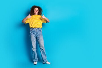 Full length photo of lovely young lady thumb up approve dressed stylish striped yellow garment isolated on blue color background