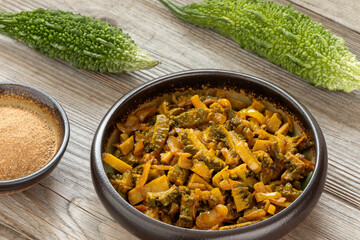 Punjabi-style bitter gourd curry (Karela Sabji in Hindi) with onion, dry mango powder, and spices....