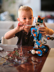 A young child is depicted using a tool to fix a colorful robot toy, emphasizing creativity and...