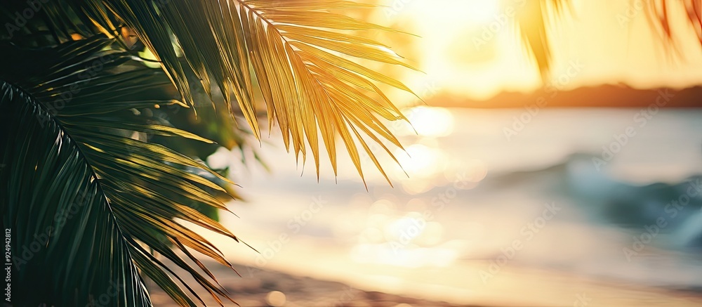 Poster blurred beautiful green palm leaves on a tropical beach with bokeh sunlight and waves create an abst