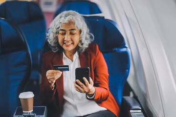 An adult woman sits by the window on a passenger plane, eagerly traveling abroad. She gazes at the...