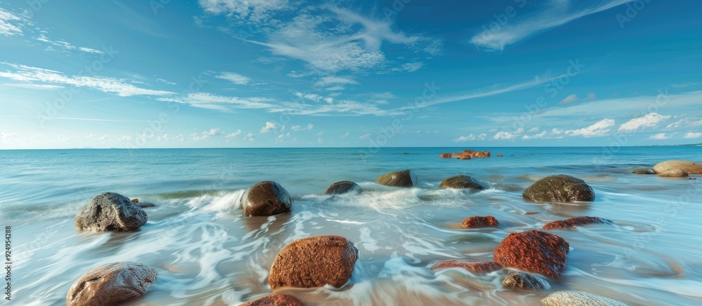 Poster Two large boulders in shallow blue ocean water long exposure image. with copy space image. Place for adding text or design