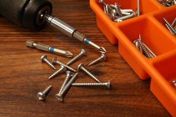 A box of screws and a screwdriver on a dark wooden table. 